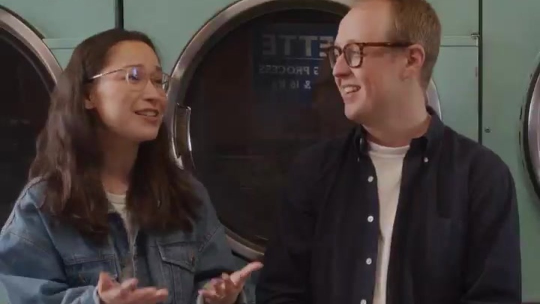 Laura and Hugo Raymond chatting on a bench in a launderette